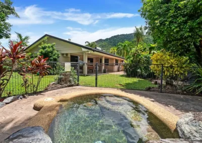 An outdoor spa and garden area of a home with an enhanced, bright blue sky for real estate marketing.